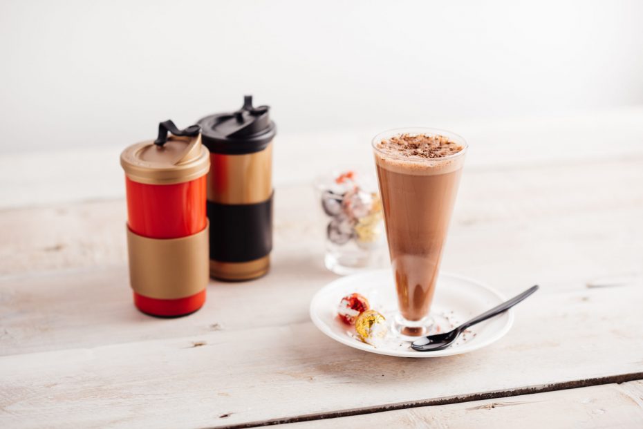 Latte in tall glass and reusable coffee cups