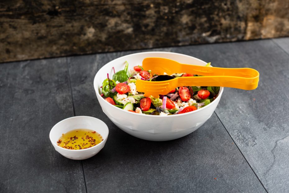 Feta Salad in a large white bowl with yellow serving tongs