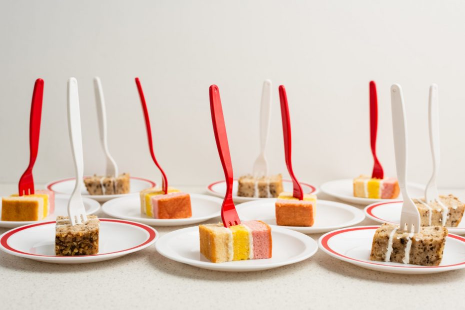 Cakes served on small plates with red and white forks